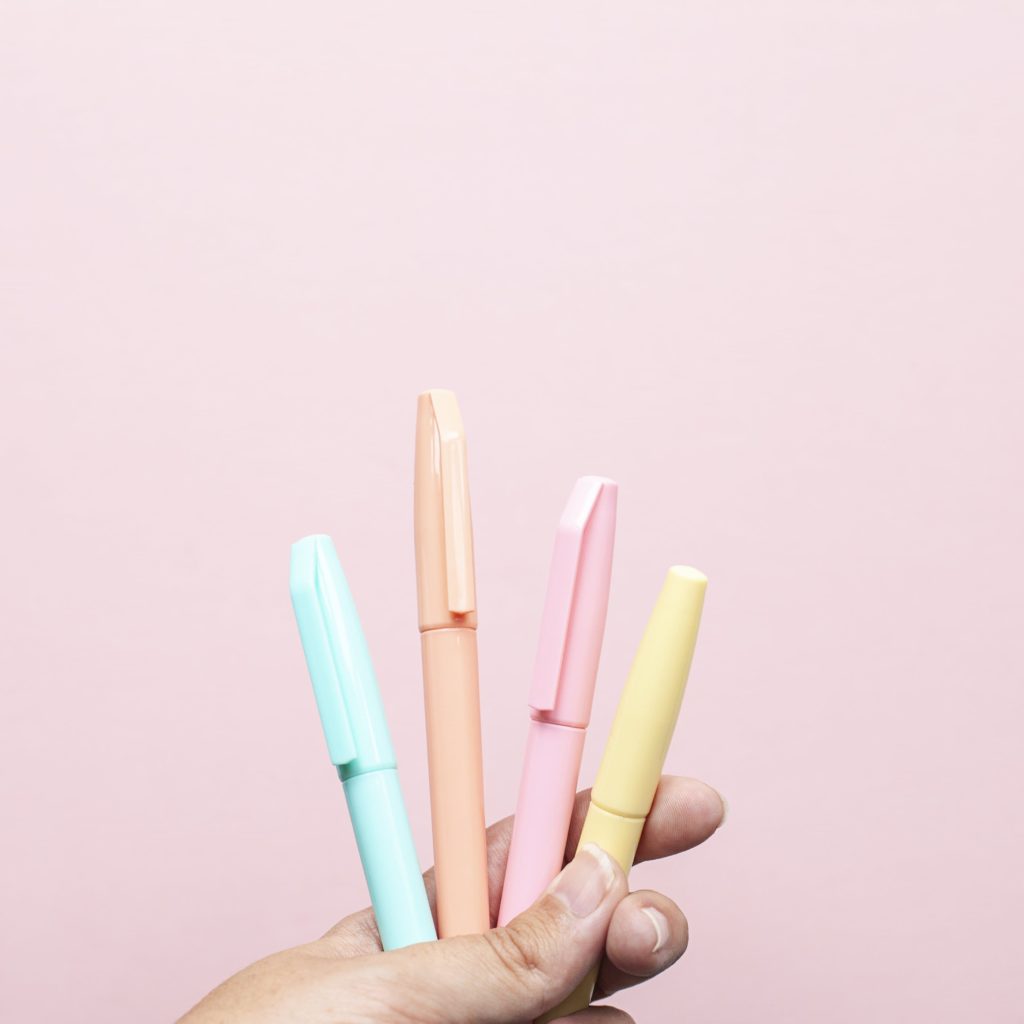 mains qui tiennent des stylos de couleurs